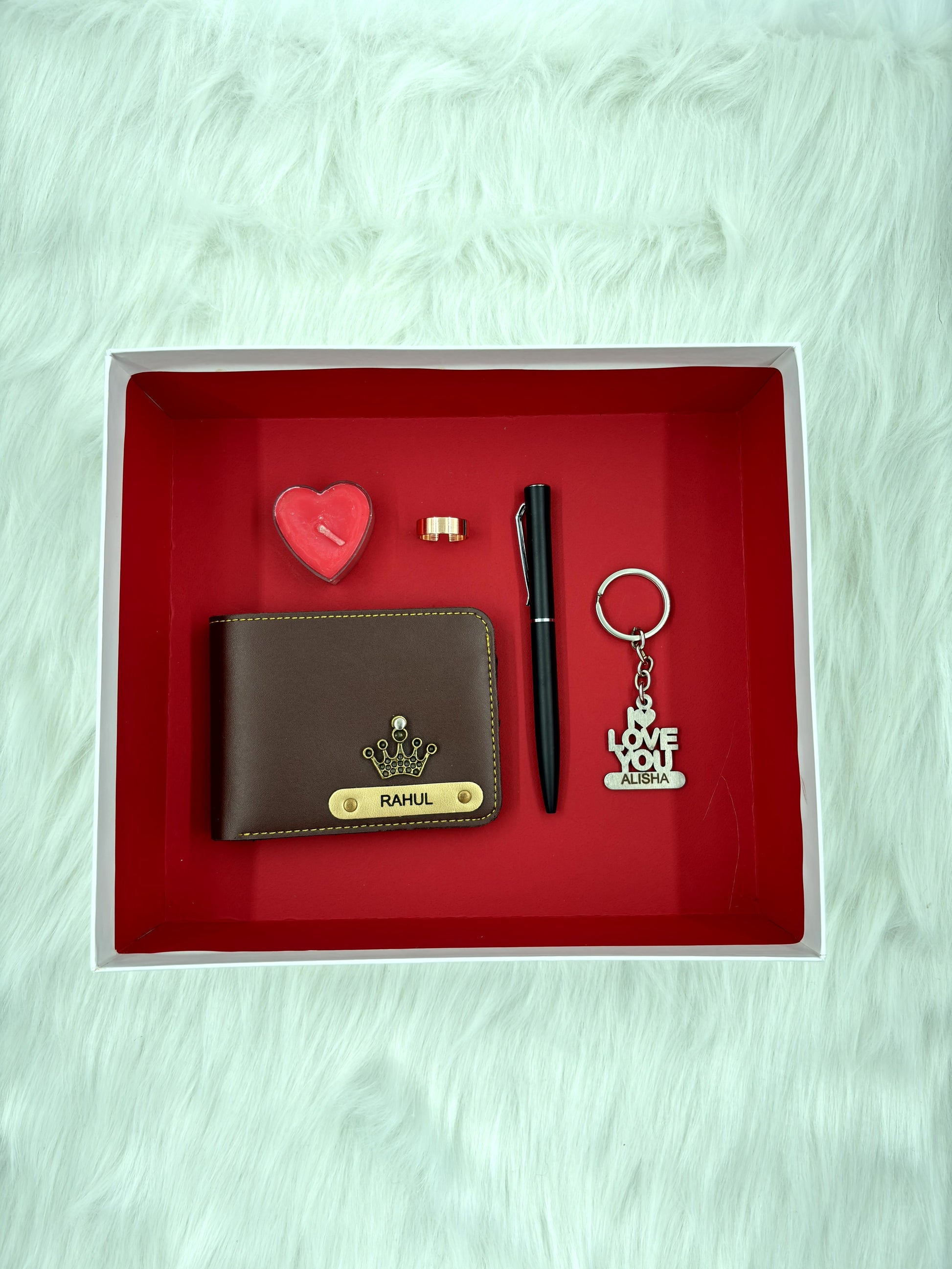 A top view of a box containing customized leather wallet, I Love You chocolate & keychain, pen, along with a gold rose and heart shaped sceneted candle