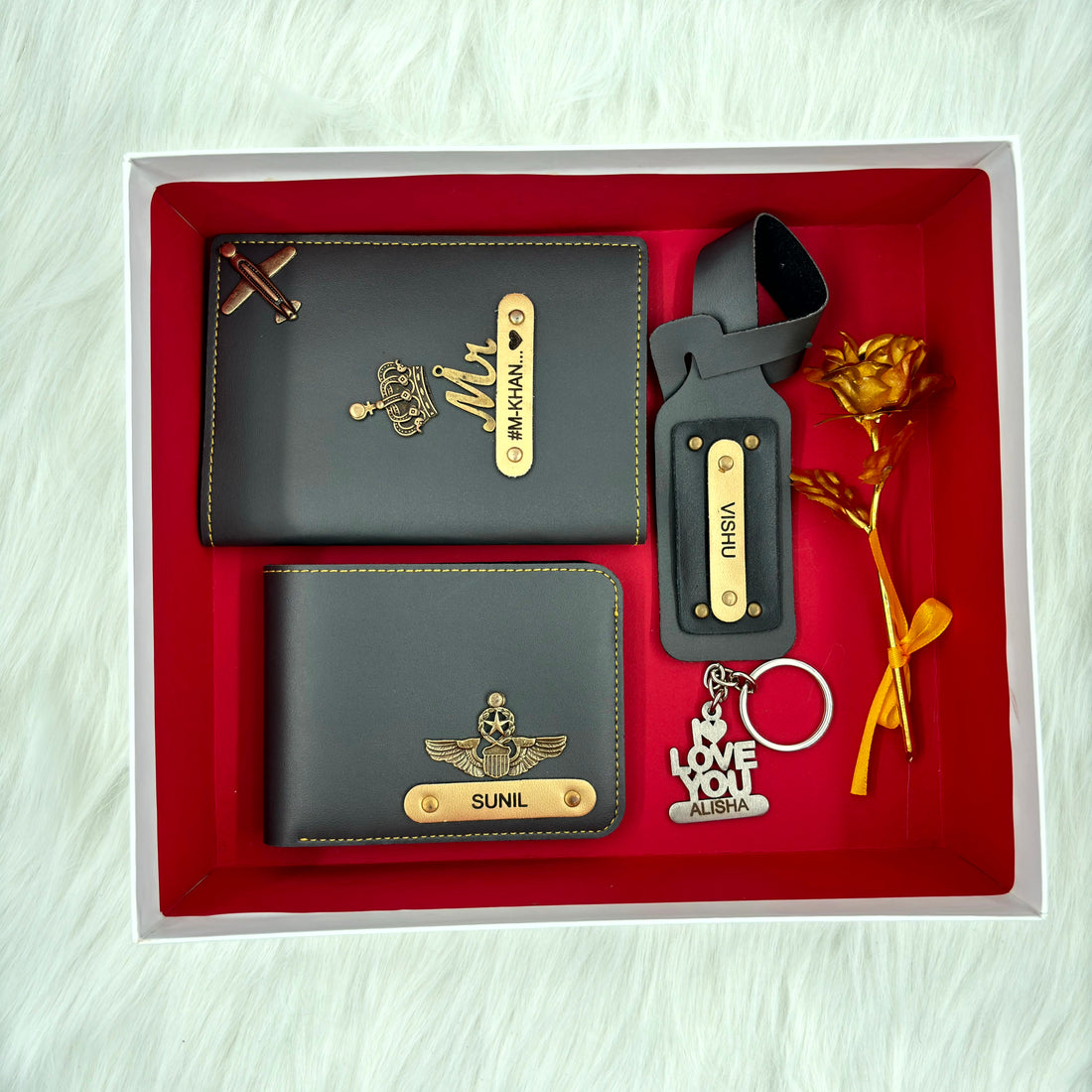 A top view of a box containing customized grey leather wallet, passport cover, luggage tag, I Love You keychain, and gold plated rose.