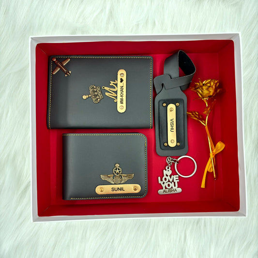 A top view of a box containing customized grey leather wallet, passport cover, luggage tag, I Love You keychain, and gold plated rose.