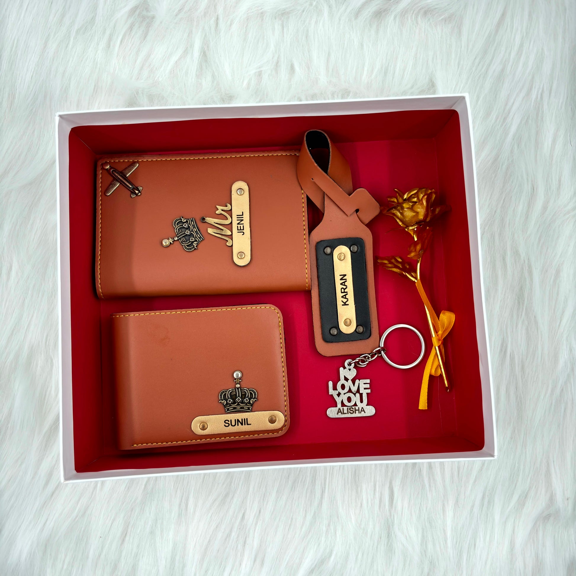 A top view of a box containing customized tan leather wallet, passport cover, luggage tag, I Love You keychain, and gold plated rose.