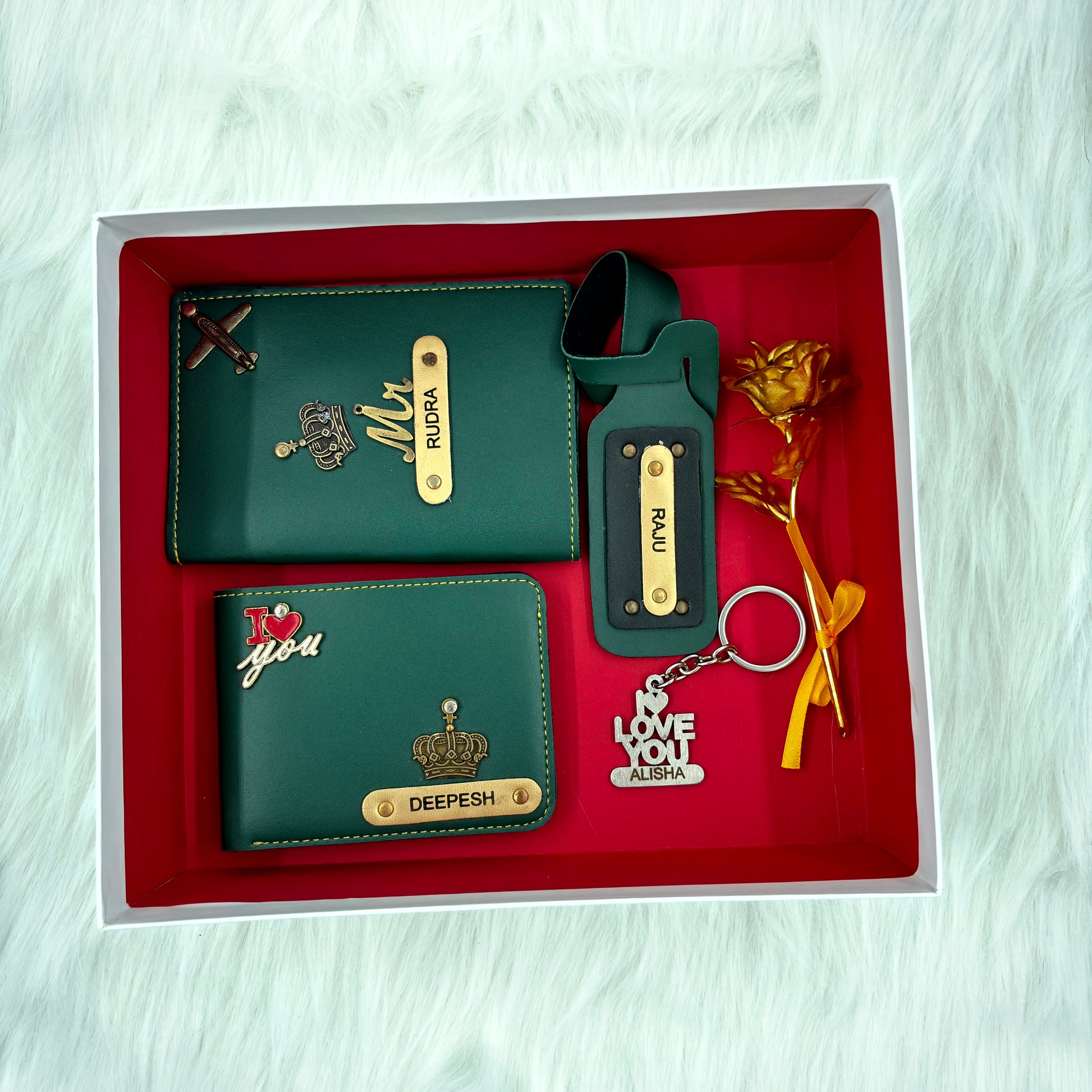 A top view of a box containing customized olive green leather wallet, passport cover, luggage tag, I Love You keychain, and gold plated rose.
