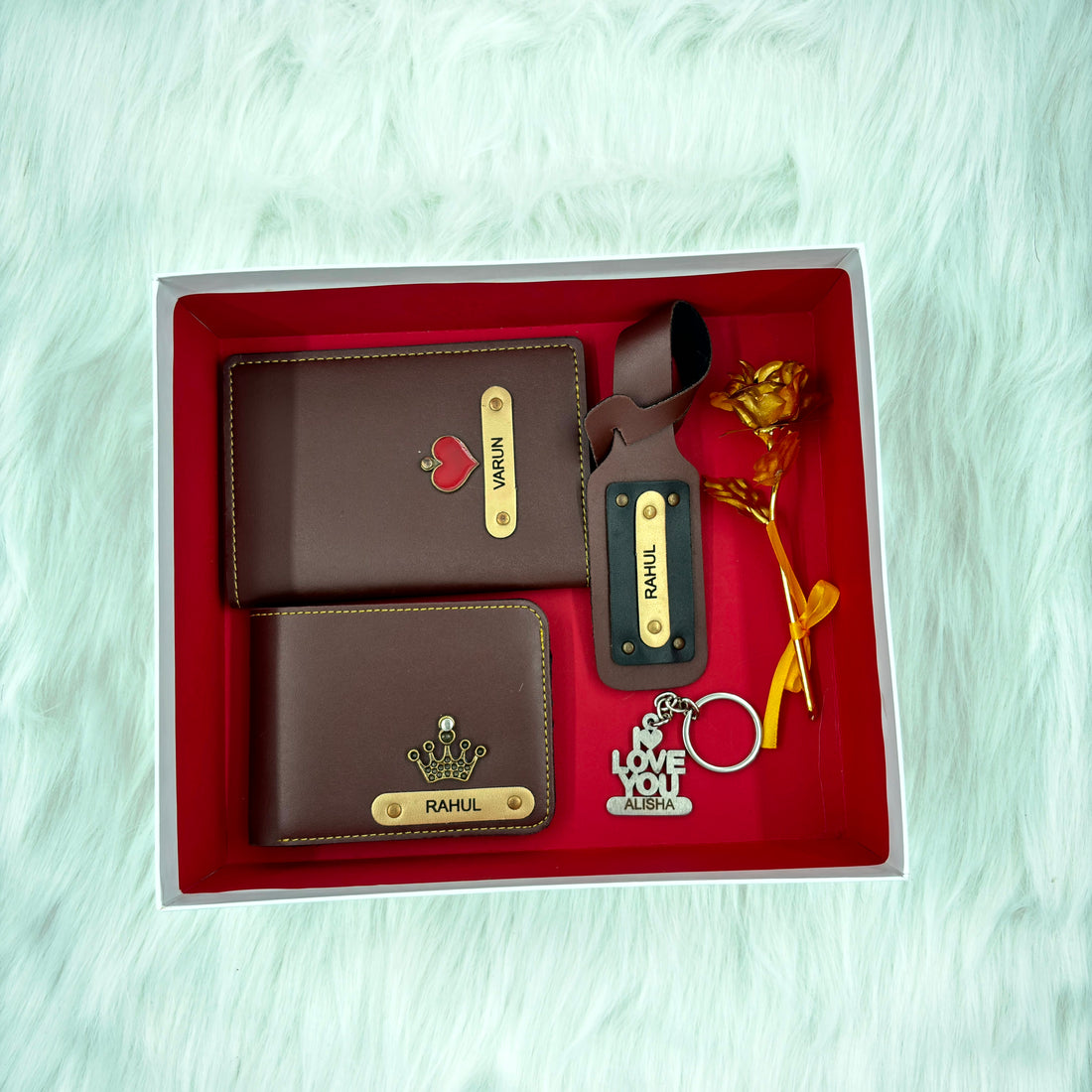 A top view of a box containing customized brown leather wallet, passport cover, luggage tag, I Love You keychain, and gold plated rose.