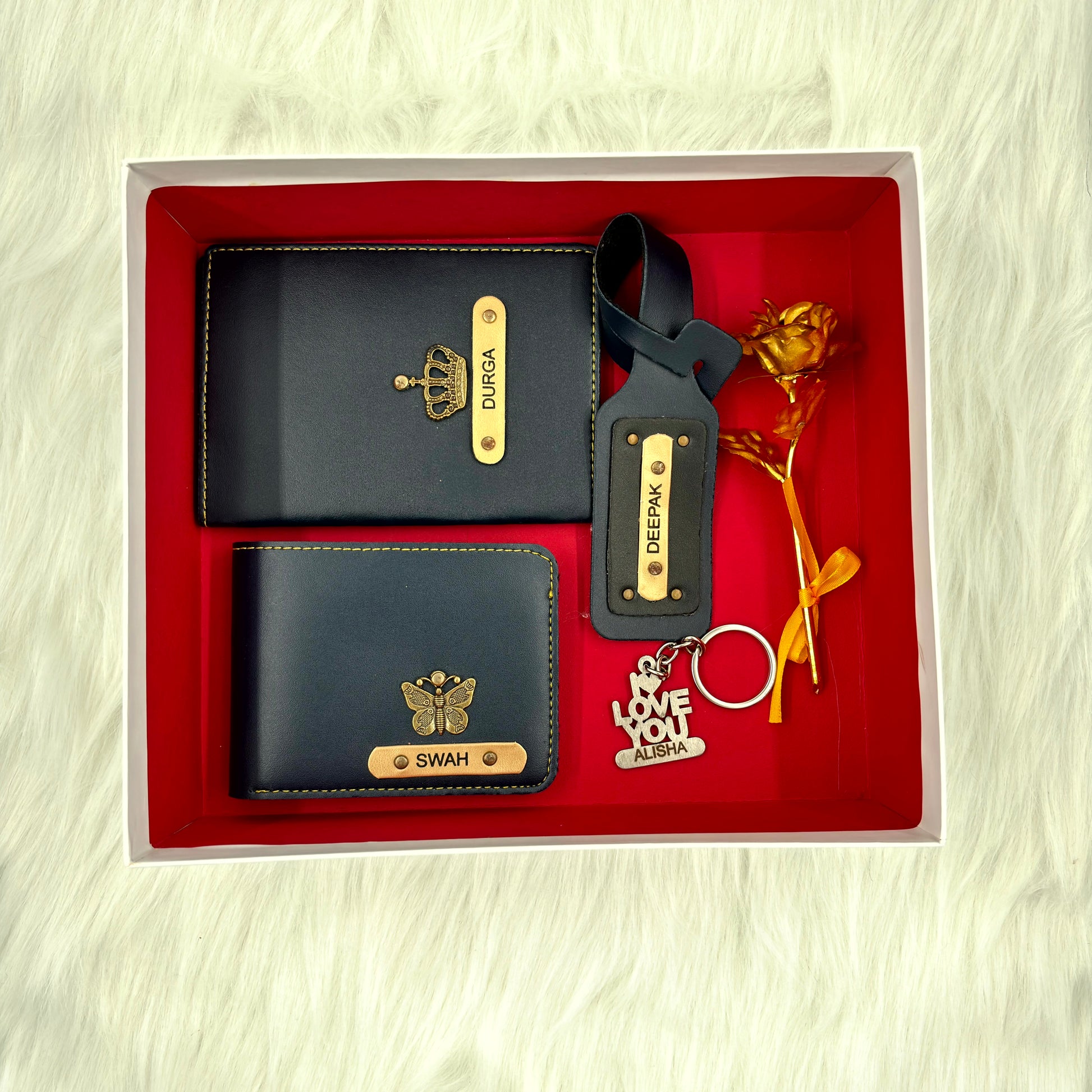 A top view of a box containing customized royal blue leather wallet, passport cover, luggage tag, I Love You keychain, and gold plated rose.