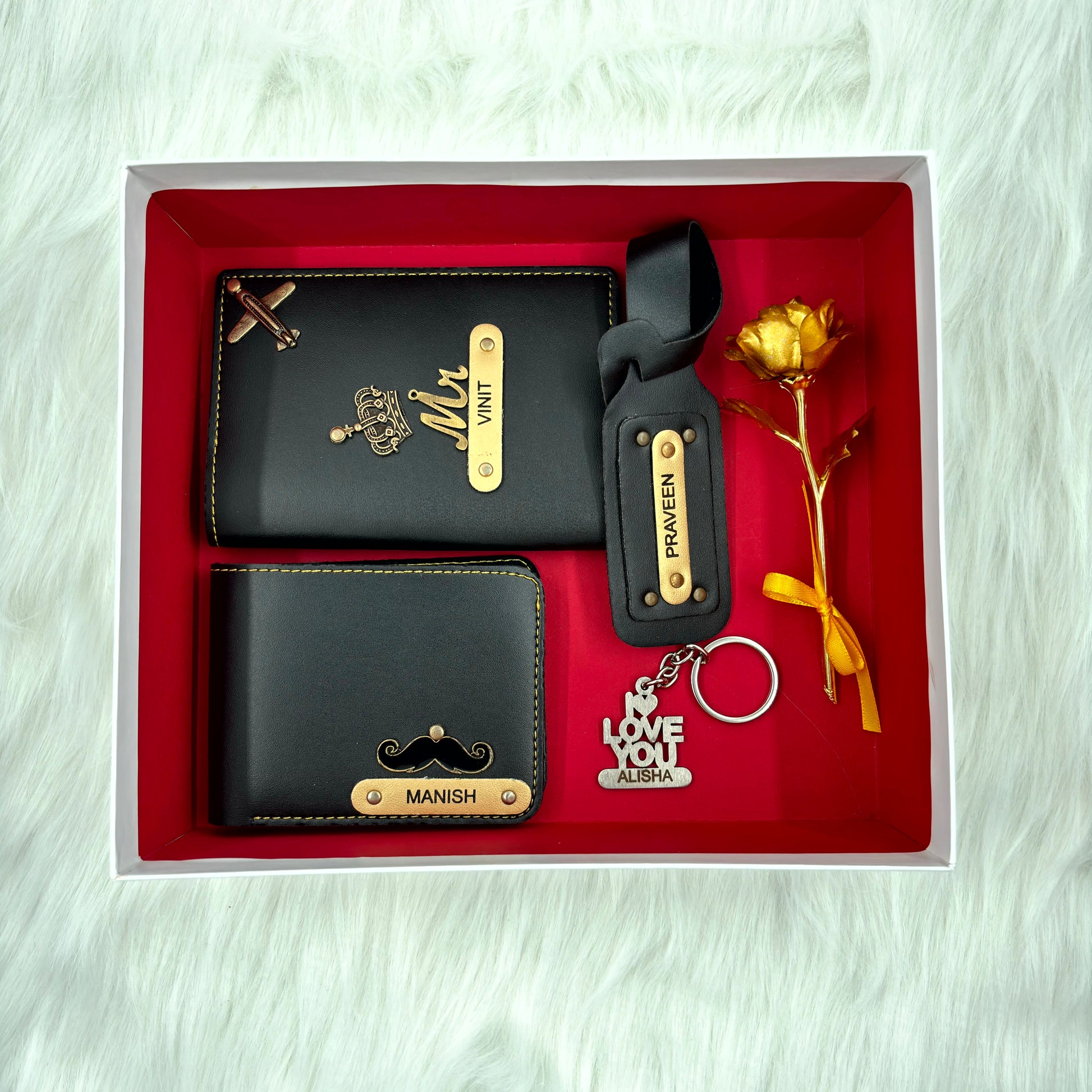 A top view of a box containing customized black leather wallet, passport cover, luggage tag, I Love You keychain, and gold plated rose.